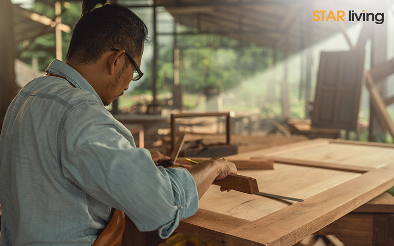 focused carpenter in a workshop measures wood for a project