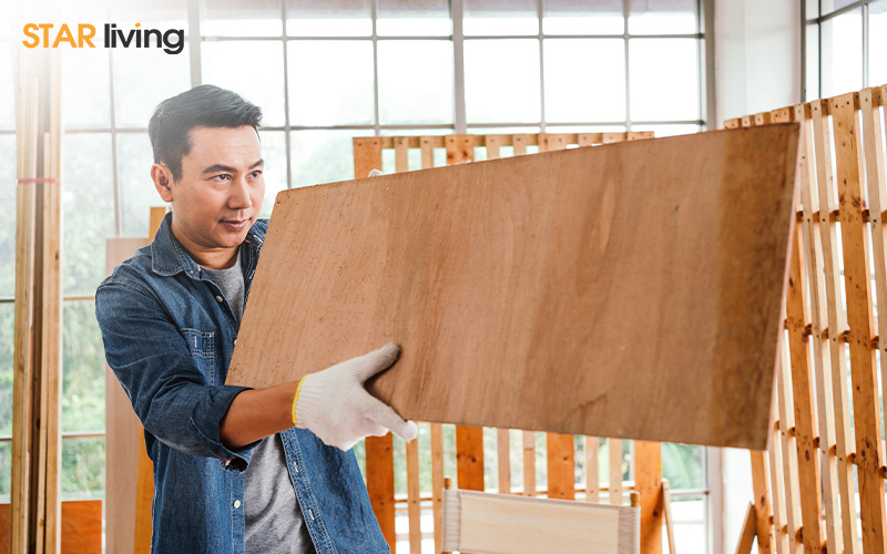 man in a denim shirt holds a wooden board
